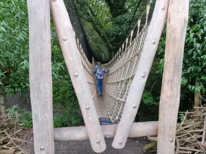 Meisje loopt over een wankelende loopbrug van touw. Foto: DagjeWeg.NL