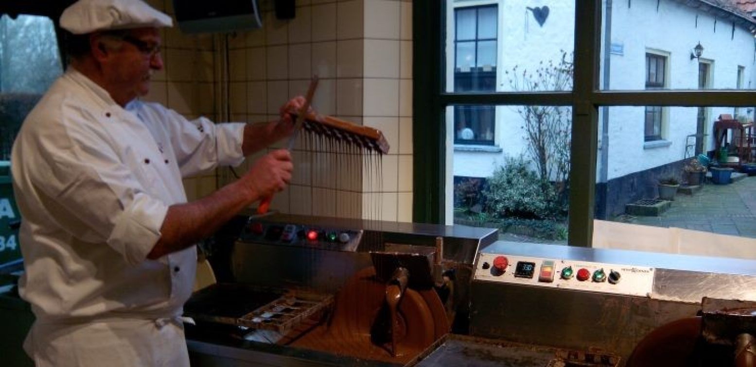 Adri Ras laat tijdens een demonstratie zien hoe de vormpjes gevuld worden met chocolade. Foto: DagjeWeg.NL