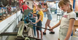 Alle kinderen blij met een dagje uit naar De Spelerij! Kinderen van groep 7 en 8 werken op de metaalafdeling van De Uitvinderij. Foto: De Spelerij - Uitvinderij.