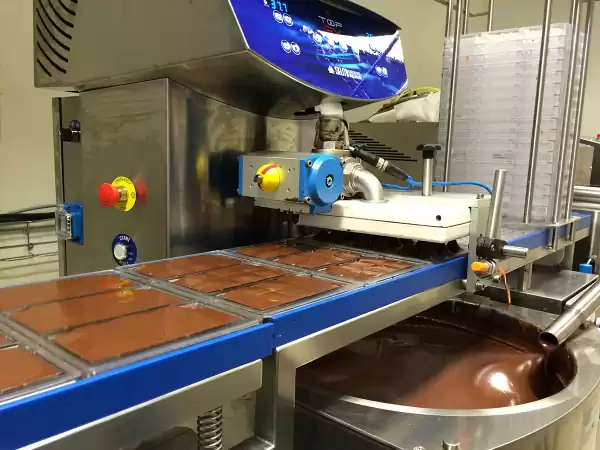 Geen chocoladerivier met waterval, maar wel vloeibare chocolade die in de vormen stroomt. Foto: Chocolatemakers Geen chocoladerivier met waterval, maar wel vloeibare chocolade die in de vormen stroomt. Foto: Chocolatemakers