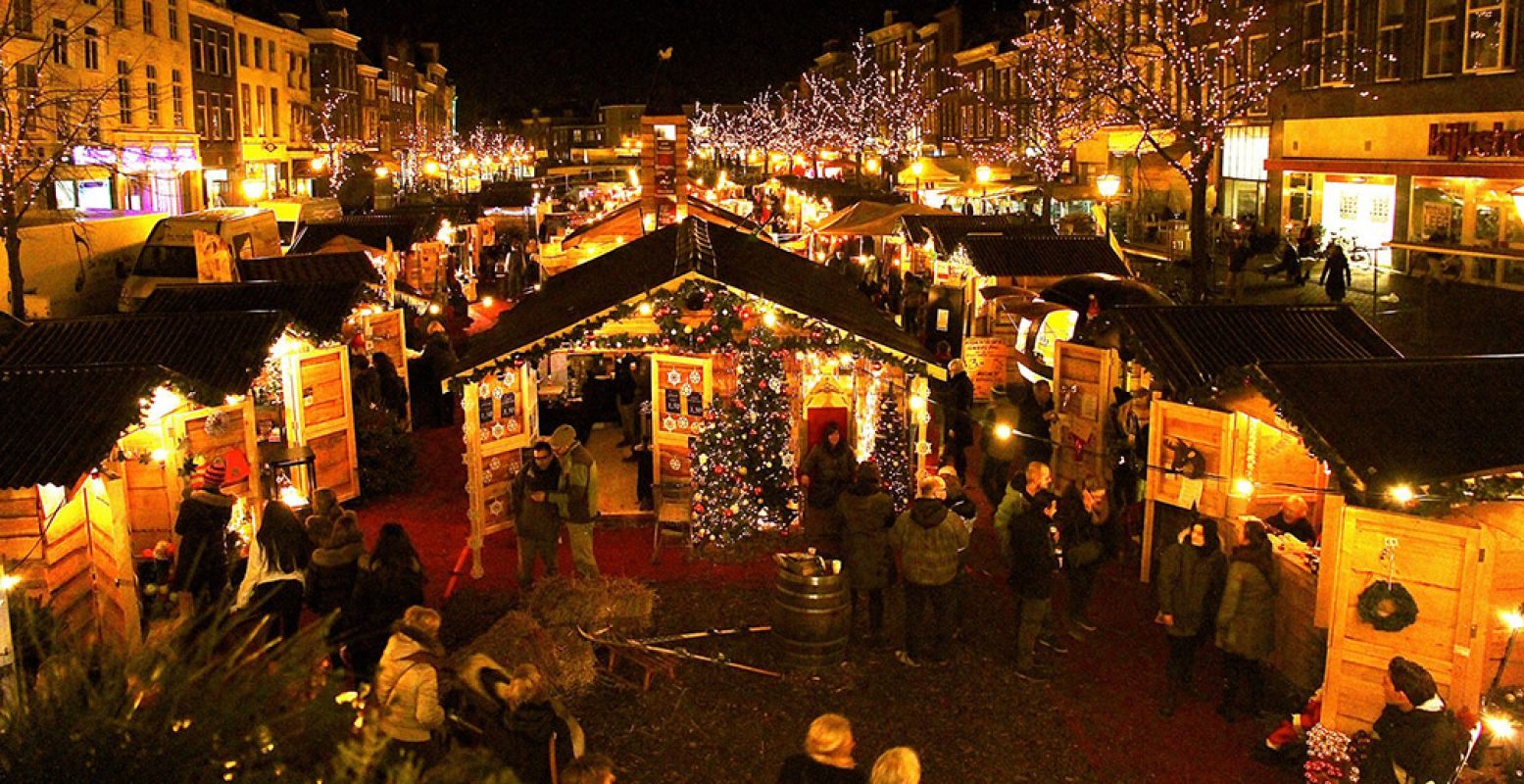 De drijvende kerstmarkt in Leiden. Lichtjes reflecteren in het water tussen de kerstchaletjes. Foto: Leiden Marketing