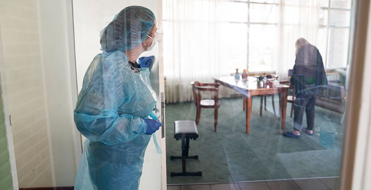 Een verpleegster checkt één van haar patiënten. Hoe zwaar is het werk als je helemaal ingepakt bent om niet besmet te raken? Foto: Museum van de Geest © Inge Hondebrink
