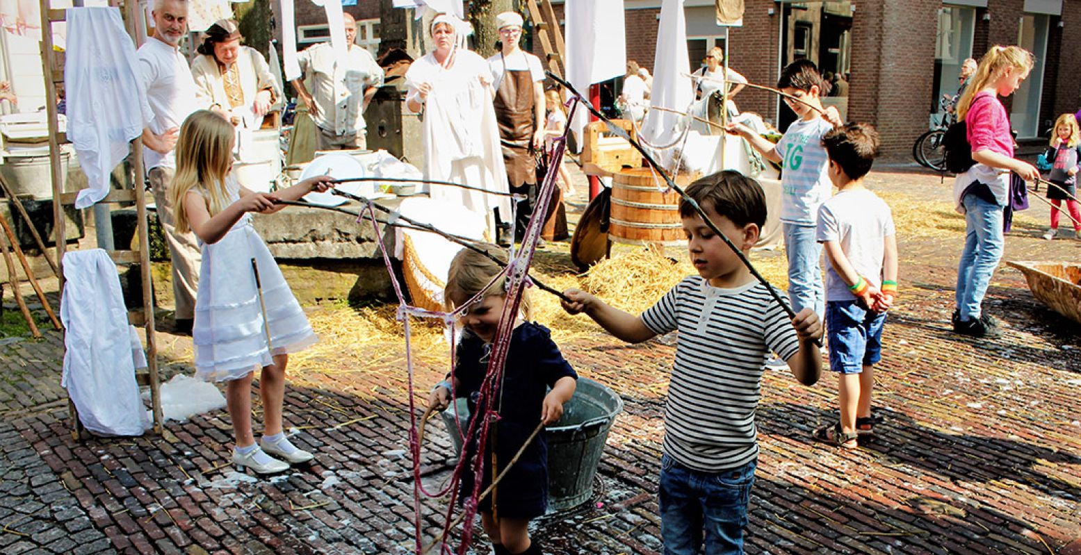 Kinderen proberen enorme zeepbellen te maken bij de wasvrouwen. Overal zijn kinderaciviteiten te vinden tijdens Historisch Spektakel Grave. Foto: Jan Lamers