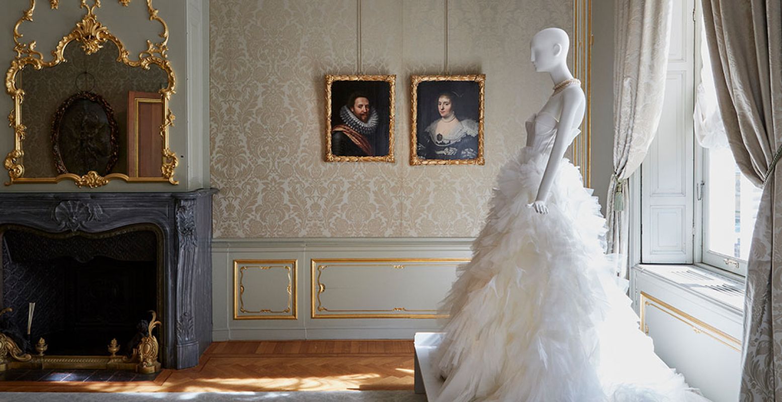 Een fraaie witte jurk naast de portretten die het ontwerp inspireerden. Foto: Nicole Marnati - locatie Hoogsteder Museum Stichting.