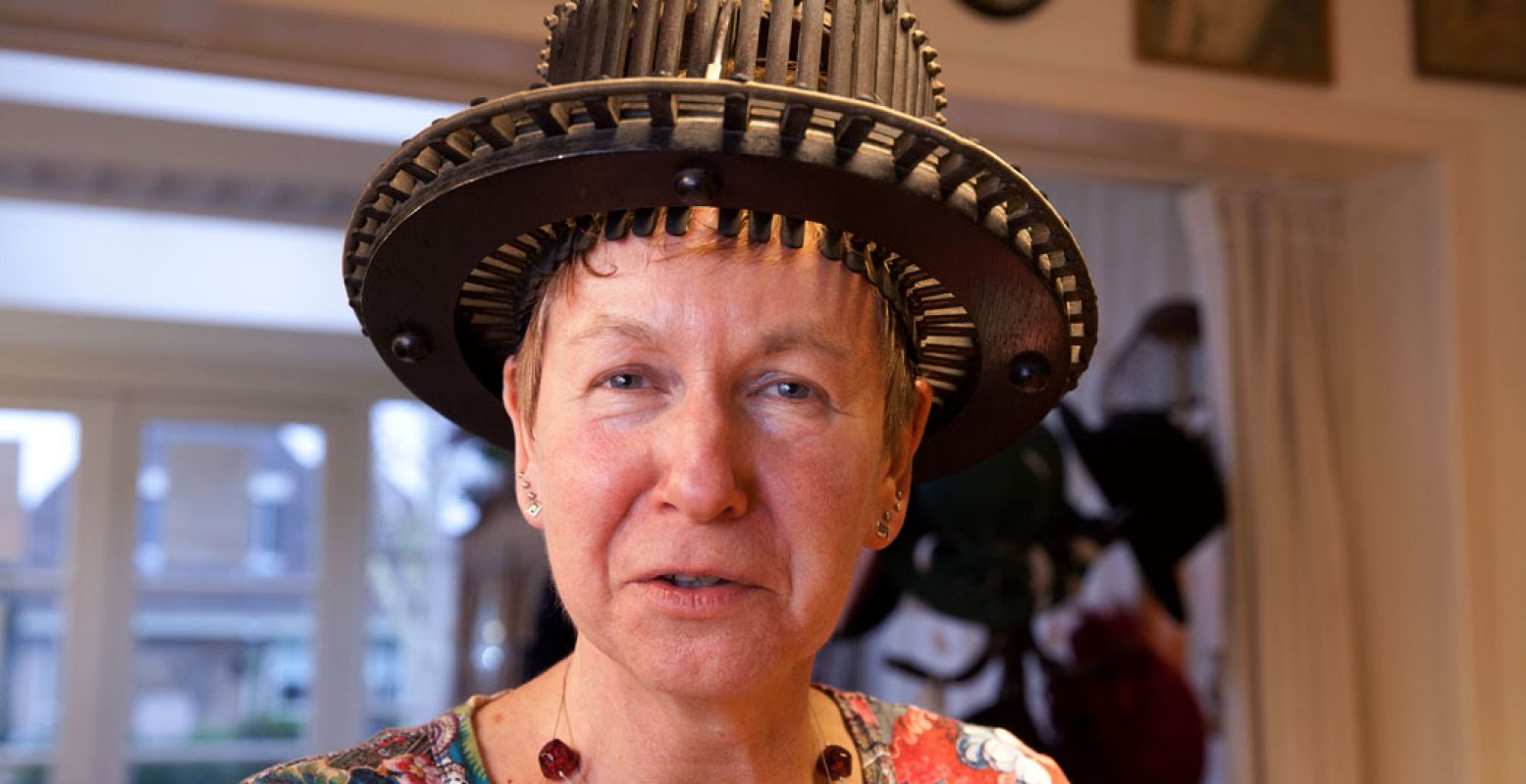 Eigenaresse Wil Gorter met een conformateur op haar hoofd: hiermee meet je de juiste maat/omvang van het hoofd voor het maken van een hoge hoed. Foto: Hoedenmuseum "Zet 'm op" © Patricia van Buuren