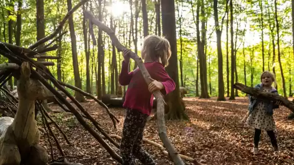 Een kind komt uit een hut van takken in het speelbos | Foto ge&uuml;pload door gebruiker Staatsbosbeheer.