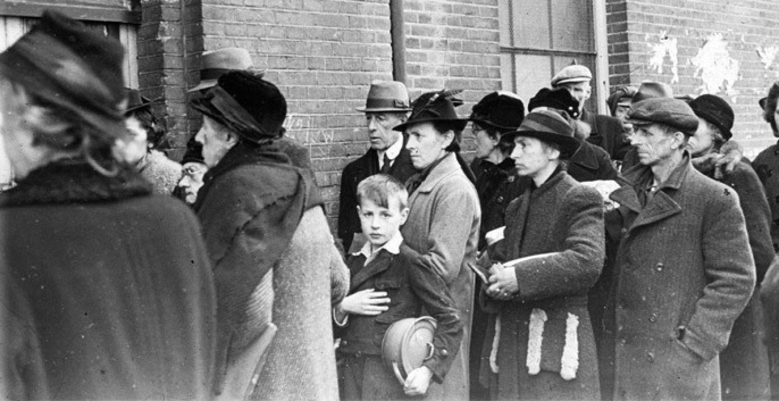 Tijdens de hongerwinter wachten inwoners voor de ingang van een schoolgebouw op hun beurt bij een voedseluitdeling van het ikb den haag 1944-45. Foto: Menno Huizinga, Nederlands Fotomuseum