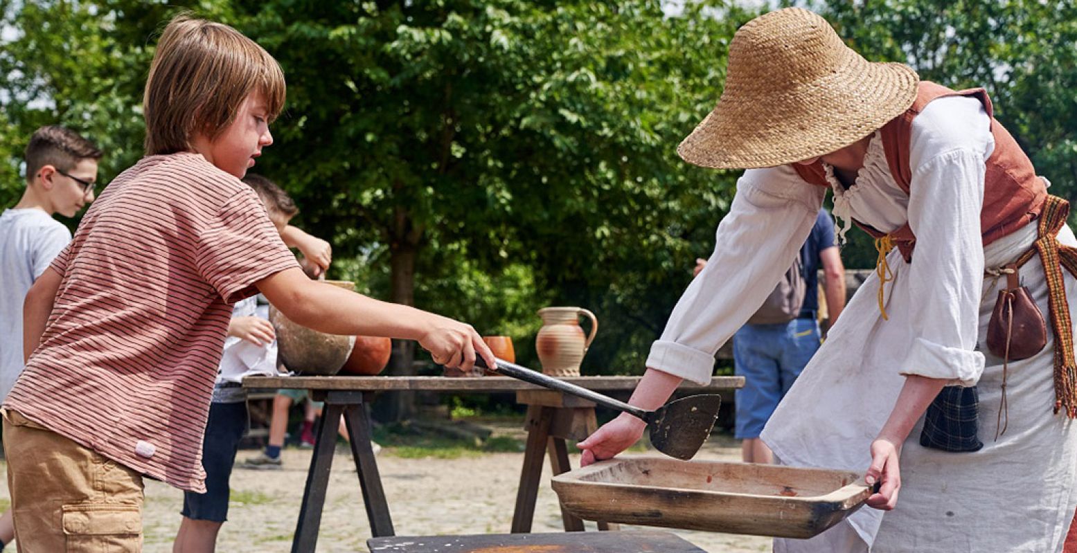 Meehelpen met het pannenkoeken bakken zoals dat vroeger gebeurde, in het preHistorisch Dorp. Foto: preHistorisch Dorp