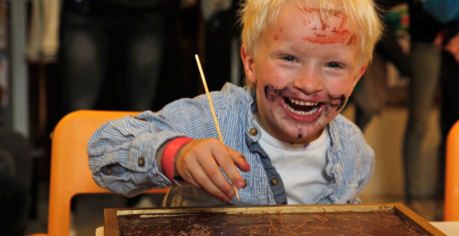 Blijde kindergezichten tijdens een workshop chocolade tekenen. Foto: Chocoa