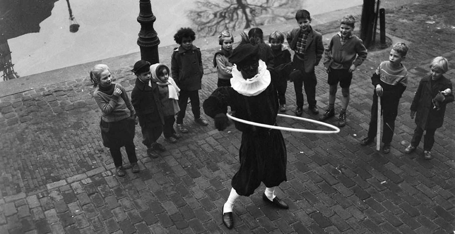 Zwarte Piet vermaakt de kinderen op straat op 27 november 1958. Bron: Onderzoeksbureau Het Citaat.