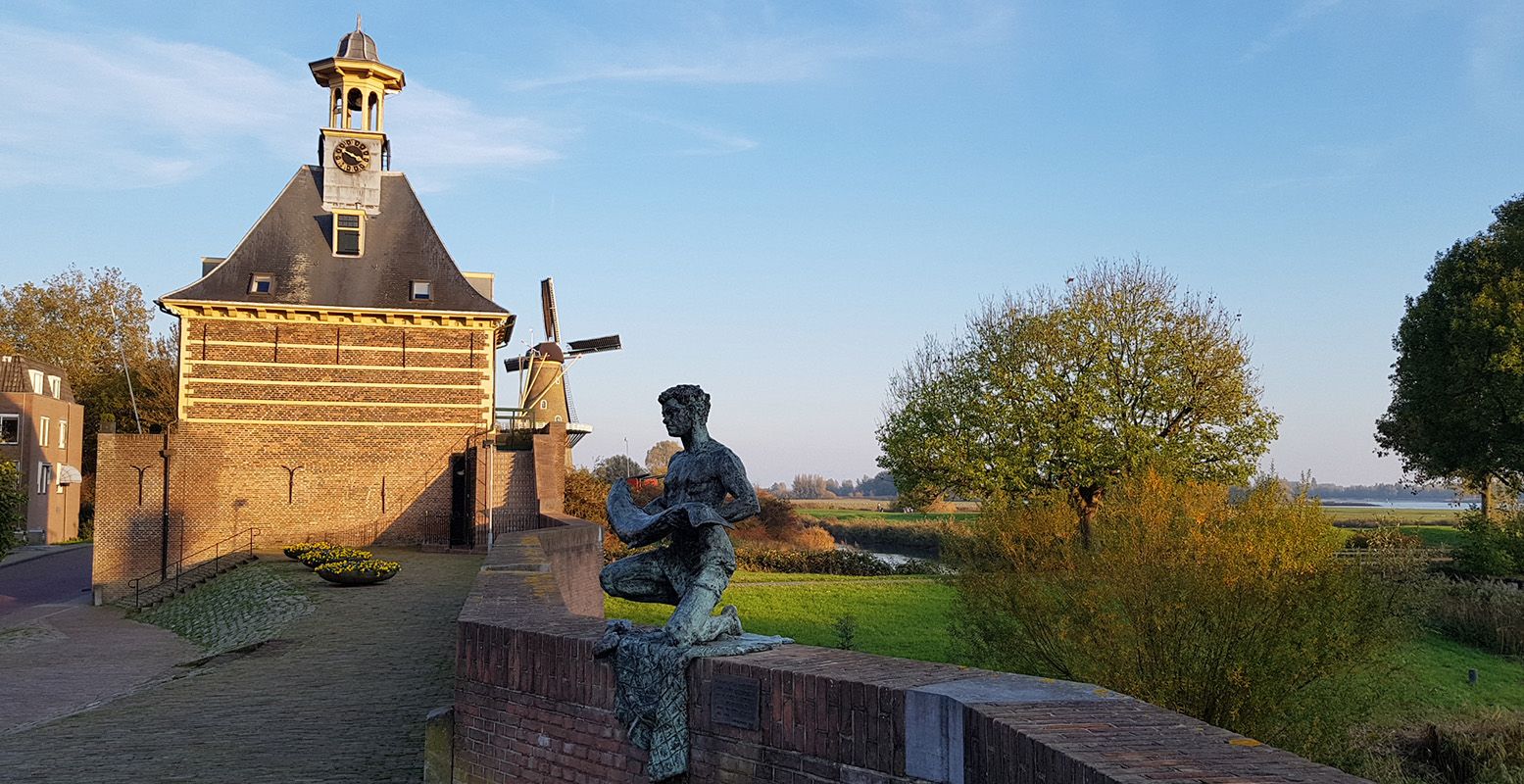 De Dalemsepoort en het beeld De Zalmvisser vanaf de vestingmuur, met op de achtergrond Molen de Hoop. Foto: DagjeWeg.NL © Tonny van Oosten