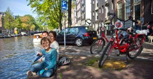Ontdek de steden van Nederland op de fiets! Ontdek Amsterdam met het hele gezin op een opvallende rode fiets van MacBike. Foto: MacBike
