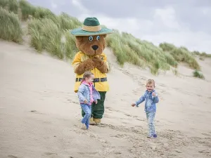 Mascotte Bollo de Beer maakt een strandwandeling.