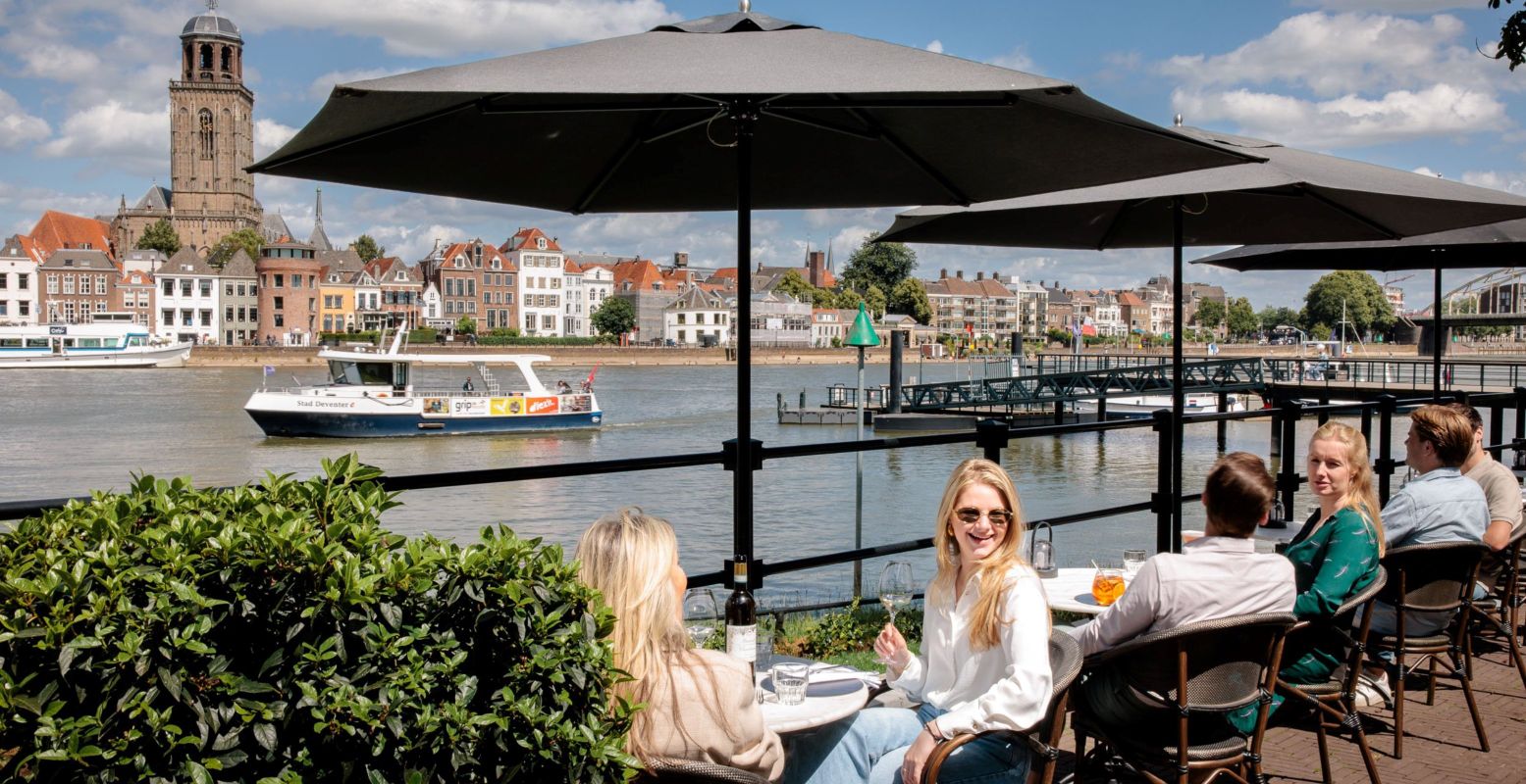 Op zonnige dagen in de zomervakantie zijn de terrasjes langs de IJssel in Deventer de place to be. Foto: Deventer Marketing © Raj Giri