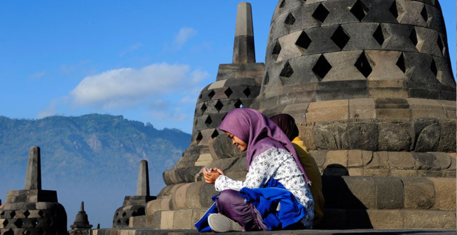 Jonge moslimmeisjes zittend bij de klokken van de stoepa, Borobudur tempel.
