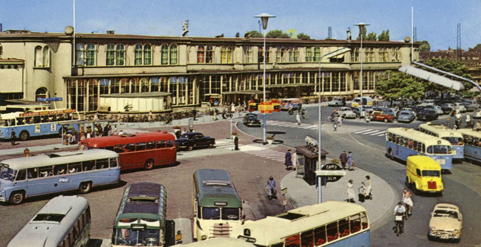 Een kleurrijk stationsplein vol kekke voertuigen in de tijd van de flowerpower. Bron: Het Spoorwegmuseum.