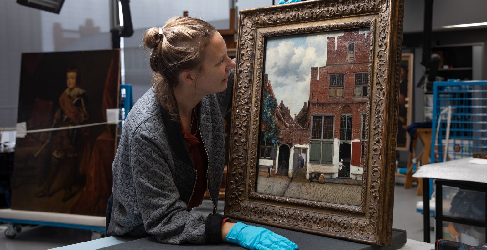 Restaurator Anna Krekeler bekijkt Het Straatje van Vermeer. Foto: Rijksmuseum © Kelly Schenk